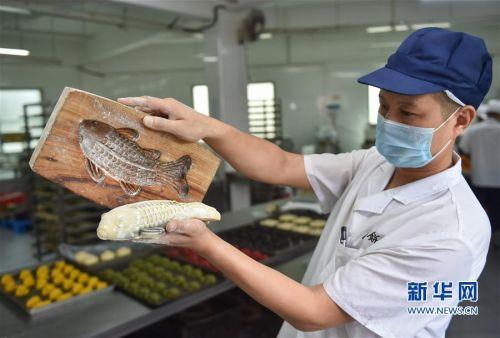 9月29日,福州老字号“百饼园”的师傅用传统手工木制模具制作“鲤鱼饼”。