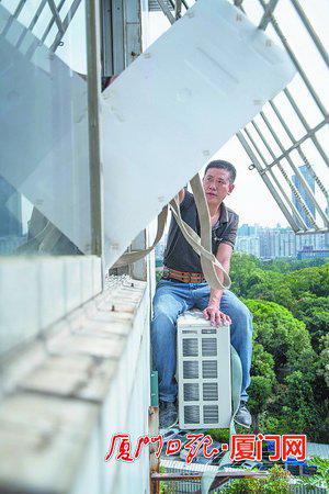 空调师傅用空调箱中的泡沫板临时顶开防盗网,坐到户外安装外机。