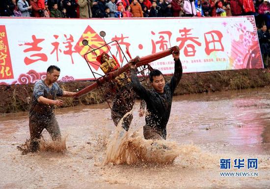 随着轰鸣的鞭炮声,几名男子抬着“五谷神”菩萨跳入方形的水田,顺着鼓点在水田里飞奔。新华网 发(施福玲摄)