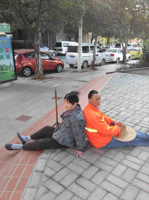 翁阿婆在自家楼下散步时突然双腿失去知觉瘫倒在路中间,附近清扫的环卫工人杨妹仔担心大冬天的老人躺在地上着凉,便坐在老人身后,用自己的背作支撑让老人依靠